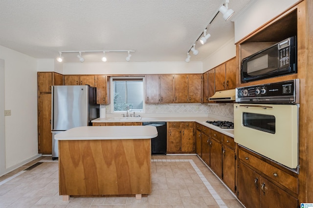 kitchen featuring sink, a center island, a textured ceiling, decorative backsplash, and black appliances