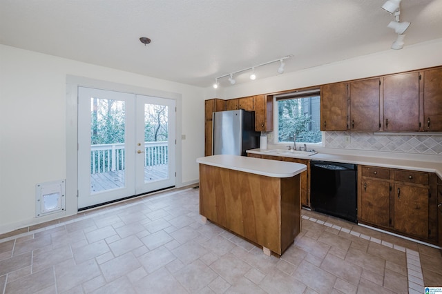 kitchen featuring french doors, sink, black dishwasher, a kitchen island, and stainless steel refrigerator