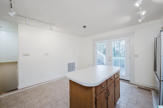 kitchen featuring french doors, track lighting, a kitchen island, and stainless steel refrigerator