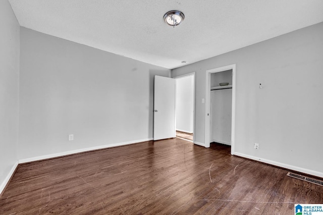 unfurnished bedroom featuring dark hardwood / wood-style floors, a textured ceiling, and a closet