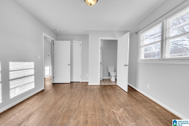 unfurnished bedroom featuring a closet, light hardwood / wood-style flooring, and ensuite bath