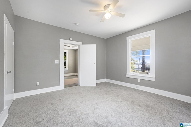 unfurnished bedroom featuring multiple windows, carpet flooring, and ceiling fan