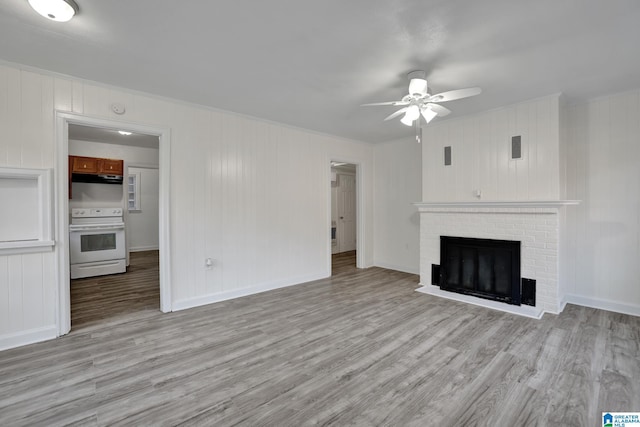 unfurnished living room featuring a fireplace, light hardwood / wood-style flooring, and ceiling fan