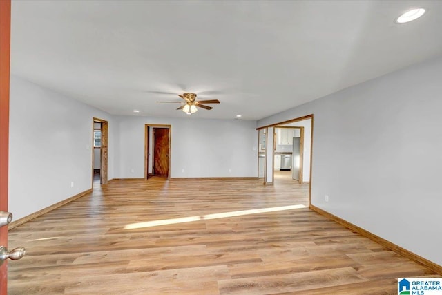 empty room with ceiling fan and light hardwood / wood-style flooring