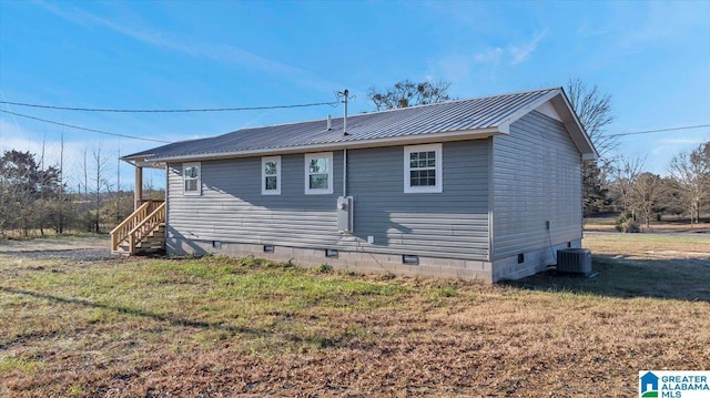 back of property featuring a lawn and central air condition unit