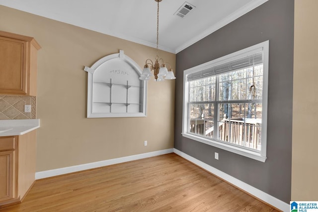 unfurnished dining area with ornamental molding, light hardwood / wood-style floors, and a notable chandelier