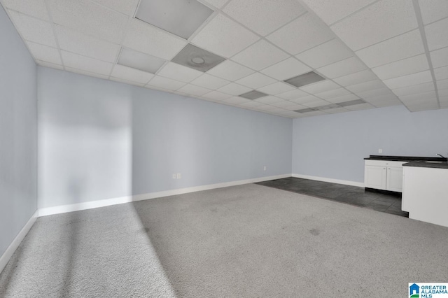 empty room featuring dark carpet and a drop ceiling