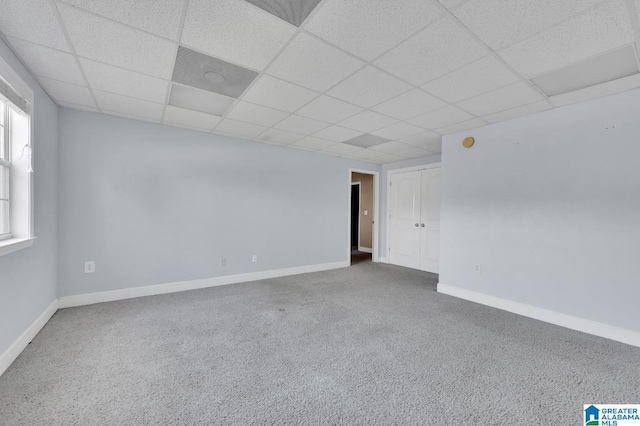 carpeted empty room with a drop ceiling