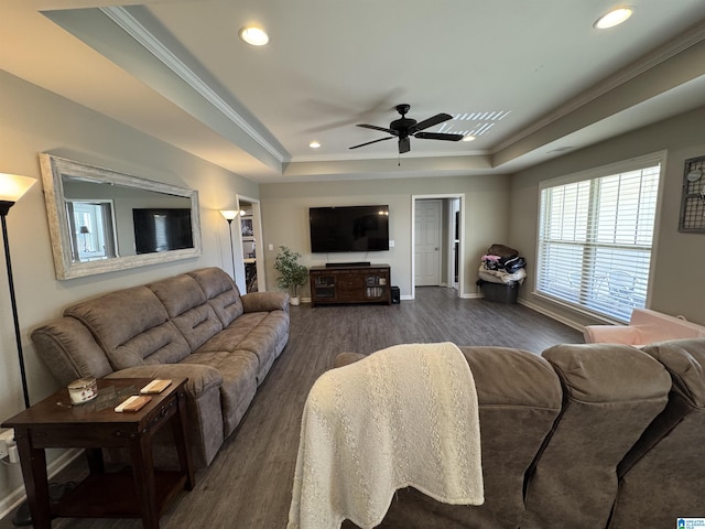 living room with a tray ceiling, ceiling fan, and dark wood-type flooring