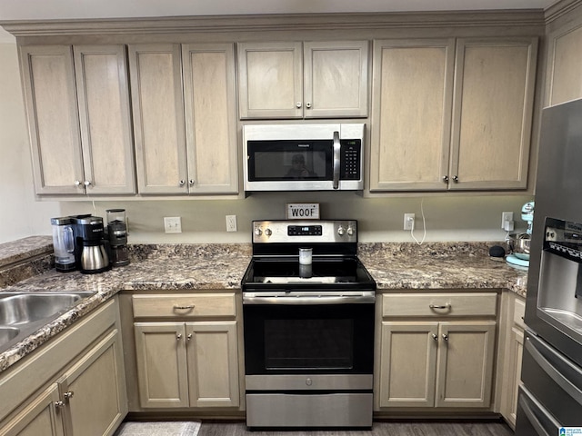 kitchen with appliances with stainless steel finishes, sink, and dark stone countertops