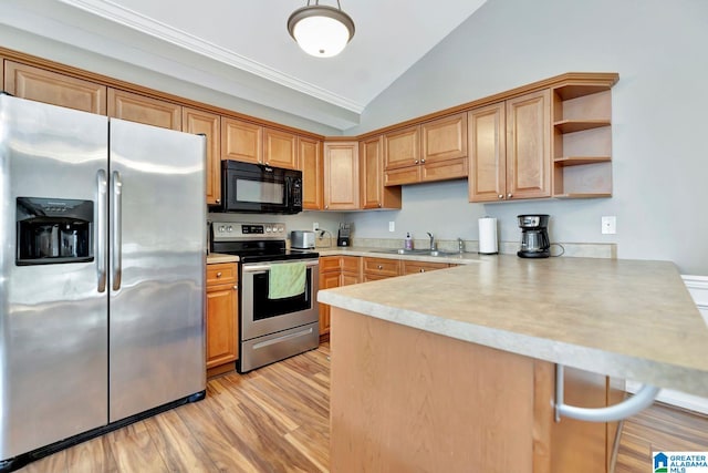 kitchen featuring appliances with stainless steel finishes, kitchen peninsula, sink, light hardwood / wood-style flooring, and lofted ceiling