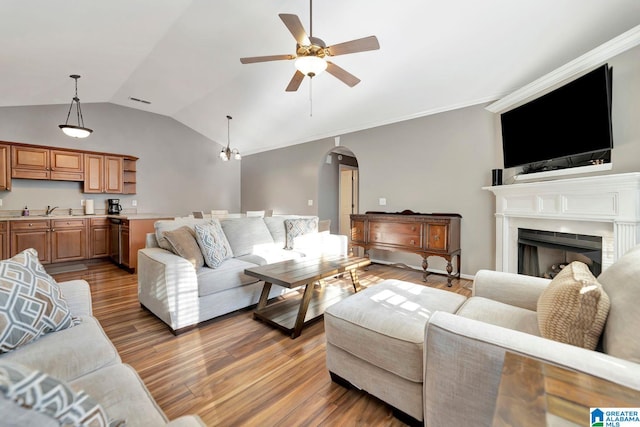 living room featuring vaulted ceiling, ceiling fan, light hardwood / wood-style floors, and ornamental molding