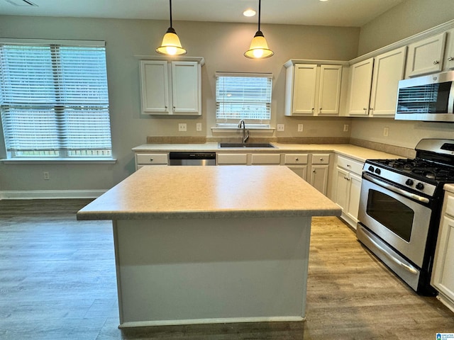 kitchen featuring white cabinets, sink, decorative light fixtures, a kitchen island, and stainless steel appliances