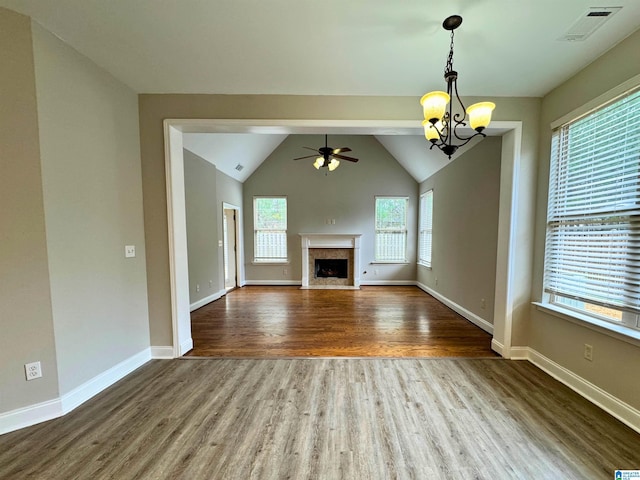 unfurnished living room featuring ceiling fan with notable chandelier, hardwood / wood-style flooring, and vaulted ceiling