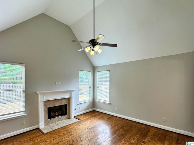 unfurnished living room with hardwood / wood-style floors, lofted ceiling, a fireplace, and a wealth of natural light