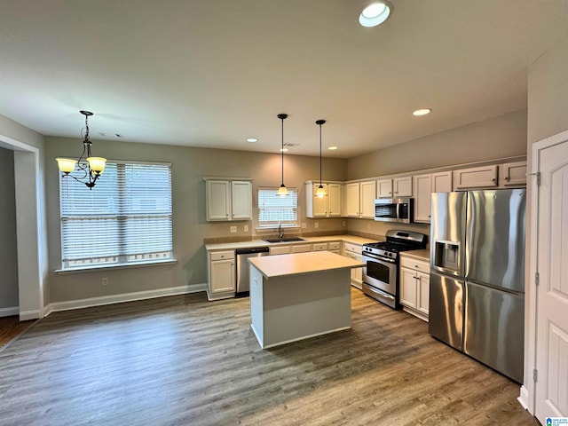 kitchen featuring stainless steel appliances, sink, decorative light fixtures, an inviting chandelier, and a center island