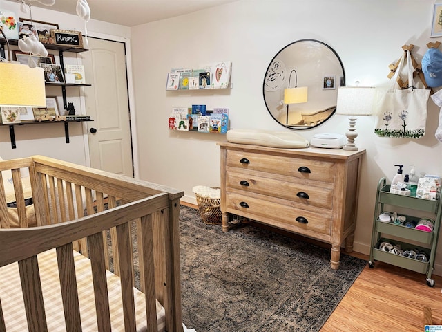 bedroom featuring a closet, a nursery area, and wood-type flooring