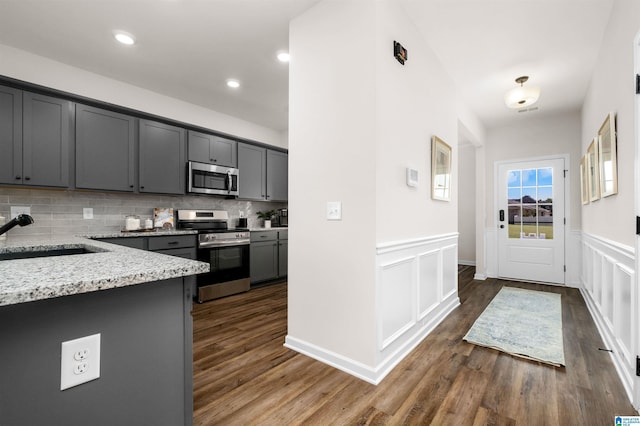 kitchen with backsplash, sink, gray cabinets, light stone countertops, and appliances with stainless steel finishes