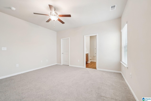 unfurnished bedroom featuring ceiling fan, light colored carpet, and connected bathroom