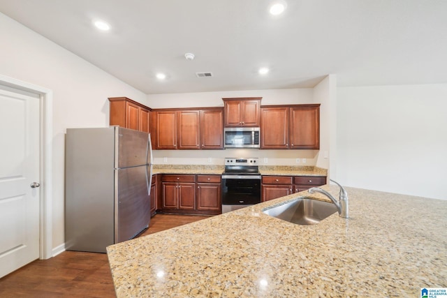 kitchen with light stone countertops, sink, appliances with stainless steel finishes, and dark wood-type flooring