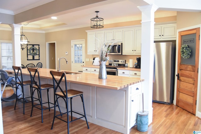 kitchen with stainless steel appliances, sink, an inviting chandelier, white cabinetry, and butcher block counters