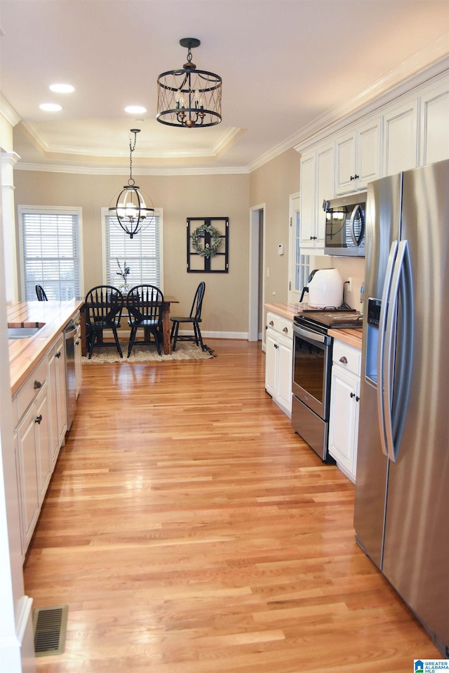 kitchen featuring butcher block counters, white cabinetry, stainless steel appliances, and a notable chandelier