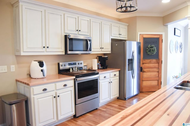 kitchen featuring light hardwood / wood-style flooring, ornamental molding, butcher block countertops, white cabinetry, and stainless steel appliances