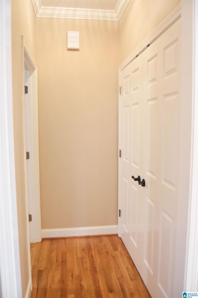 corridor with light hardwood / wood-style floors and ornamental molding