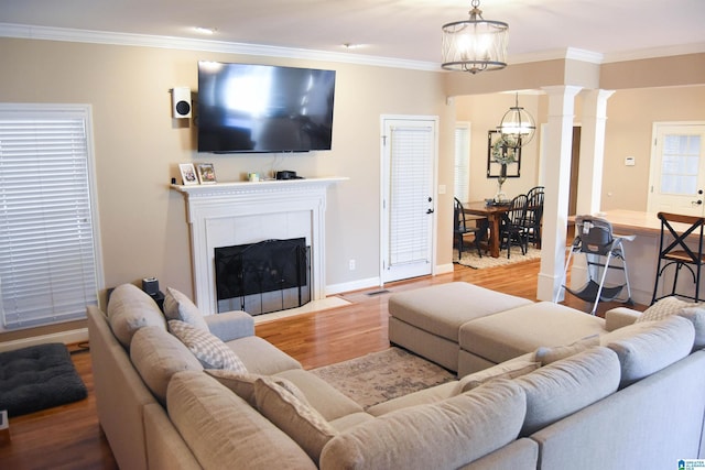 living room with a notable chandelier, ornamental molding, a tile fireplace, and light hardwood / wood-style flooring