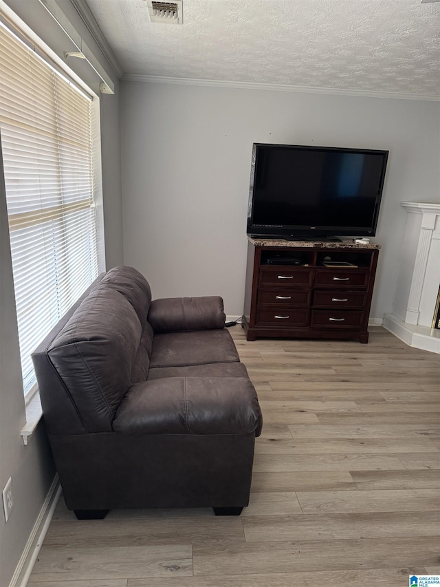 living room featuring a textured ceiling, light hardwood / wood-style flooring, and ornamental molding