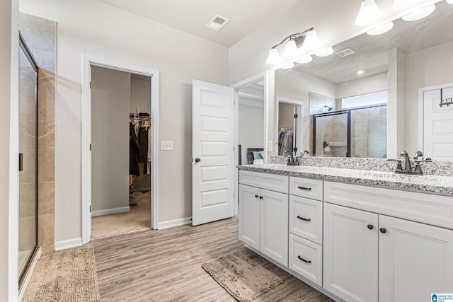 bathroom featuring hardwood / wood-style floors, vanity, and a shower with shower door