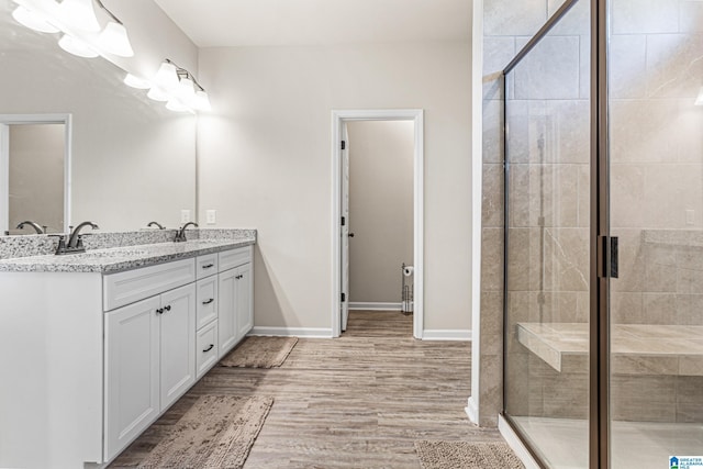 bathroom with a shower with door, vanity, and wood-type flooring