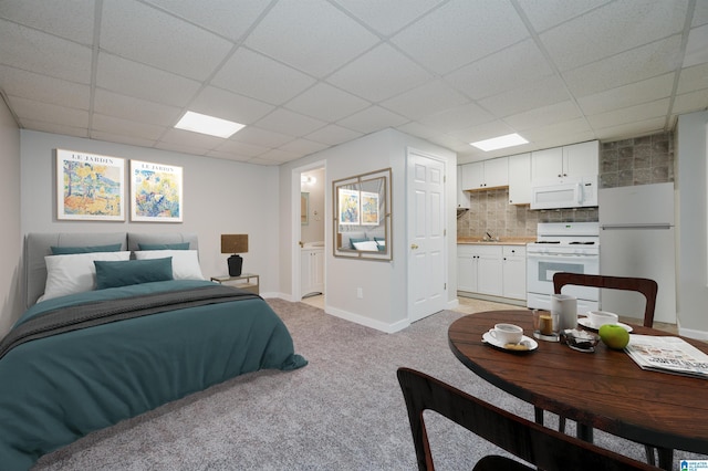 bedroom with light carpet, connected bathroom, and a paneled ceiling