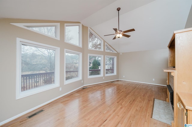 unfurnished living room featuring a tiled fireplace, light hardwood / wood-style flooring, plenty of natural light, and ceiling fan