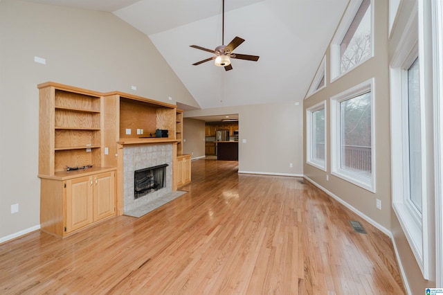 unfurnished living room with ceiling fan, light wood-type flooring, a fireplace, and high vaulted ceiling