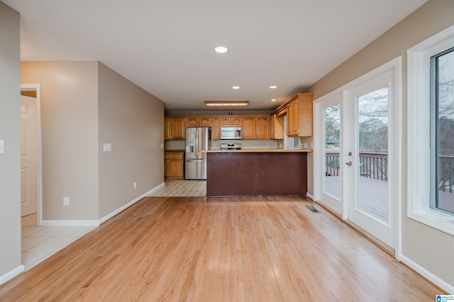 kitchen featuring french doors, stainless steel fridge with ice dispenser, kitchen peninsula, stove, and light wood-type flooring