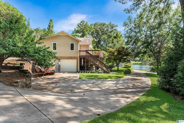 front of property with a deck with water view, a front yard, and a garage