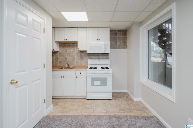 kitchen with white appliances, white cabinets, sink, light tile patterned floors, and tasteful backsplash