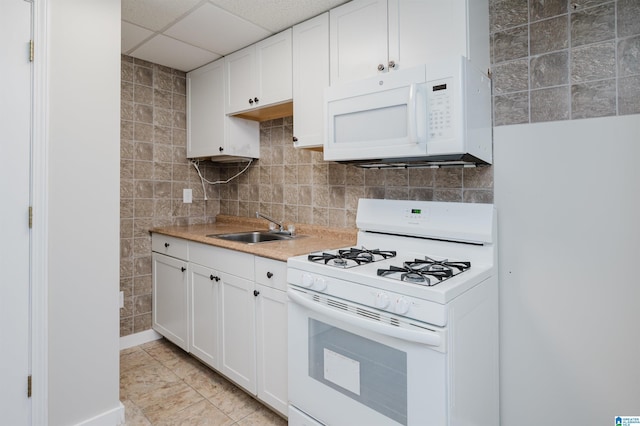 kitchen with a drop ceiling, white cabinetry, white appliances, and sink