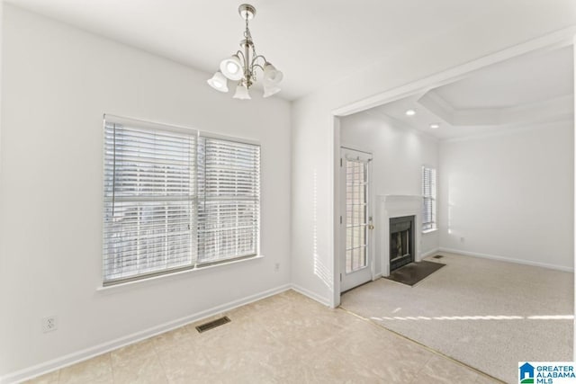 unfurnished living room featuring carpet, a tray ceiling, and a chandelier