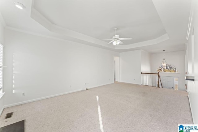 carpeted empty room featuring a tray ceiling, ceiling fan, and crown molding