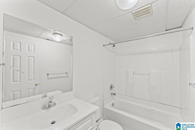 full bathroom featuring a drop ceiling, toilet, washtub / shower combination, and vanity