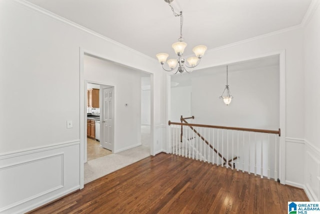 empty room featuring hardwood / wood-style flooring, a notable chandelier, and ornamental molding