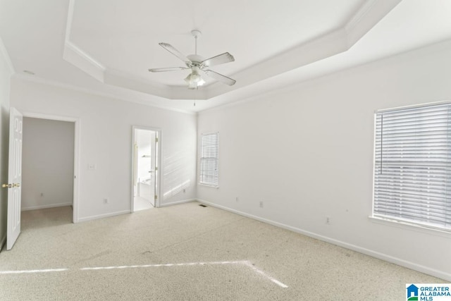 spare room with ceiling fan, a wealth of natural light, and a tray ceiling