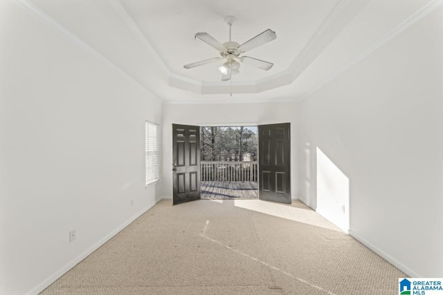 spare room with ceiling fan, a raised ceiling, light colored carpet, and ornamental molding