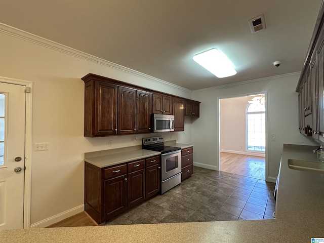 kitchen featuring dark brown cabinetry, stainless steel appliances, ornamental molding, and sink