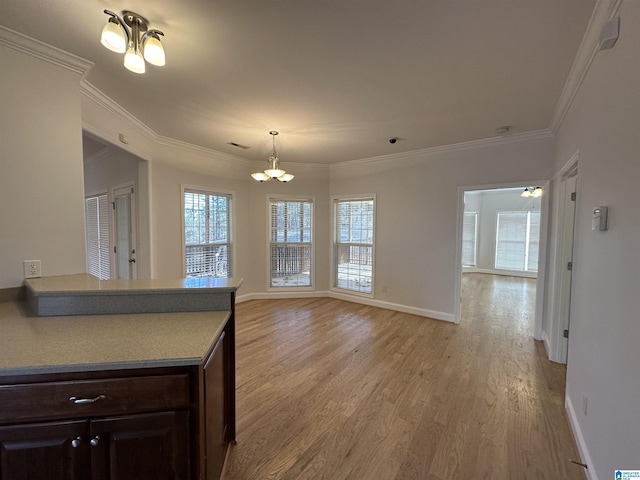 kitchen featuring dark brown cabinetry, crown molding, light wood-type flooring, and a notable chandelier