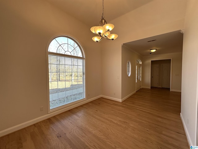 empty room featuring hardwood / wood-style floors, an inviting chandelier, and vaulted ceiling