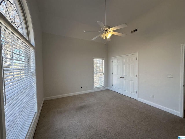 unfurnished bedroom with ceiling fan, carpet floors, high vaulted ceiling, and a closet