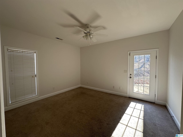 unfurnished room featuring ceiling fan and dark colored carpet